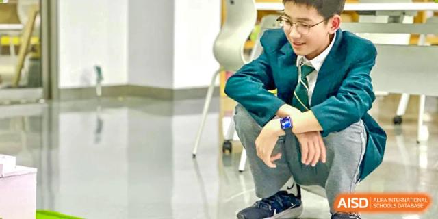 A student at Shanghai International High School of BANZ looks down at his phone while sitting in a classroom.