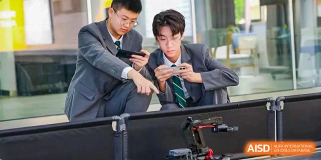 Two students at Shanghai International High School of BANZ work on a project with a 3D-printed robot.