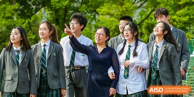 A teacher at Shanghai International High School of BANZ points to something outside the window while a group of students looks on.