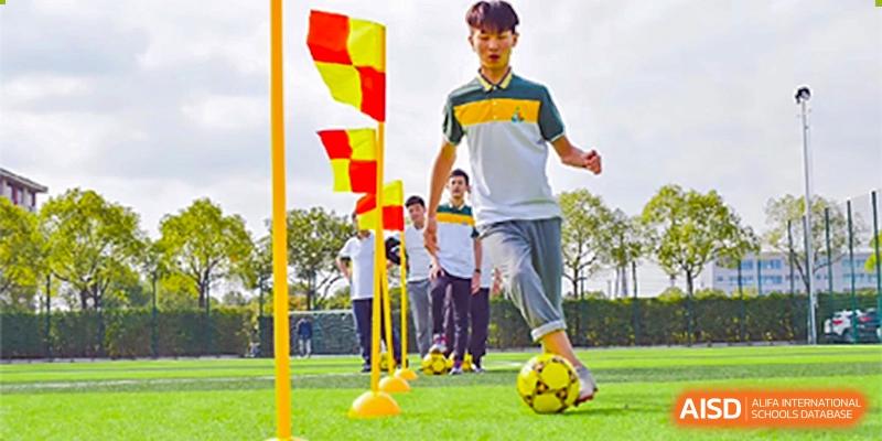 Students from Shanghai International High School of BANZ playing a soccer drill on a field.