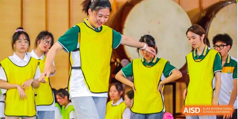 Students from Shanghai International High School of BANZ participating in a group activity with a large drum in the background.