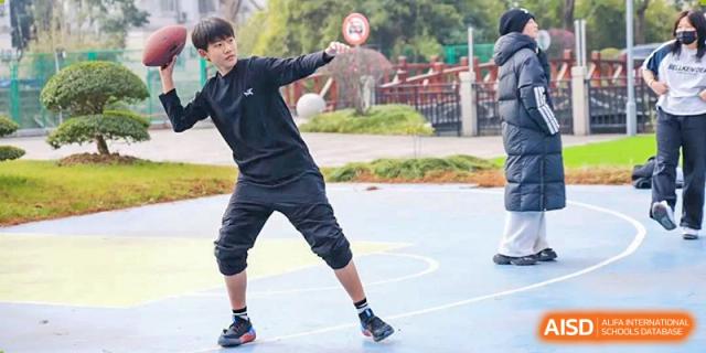 A student from Shanghai International High School of BANZ playing tennis on a blue court.