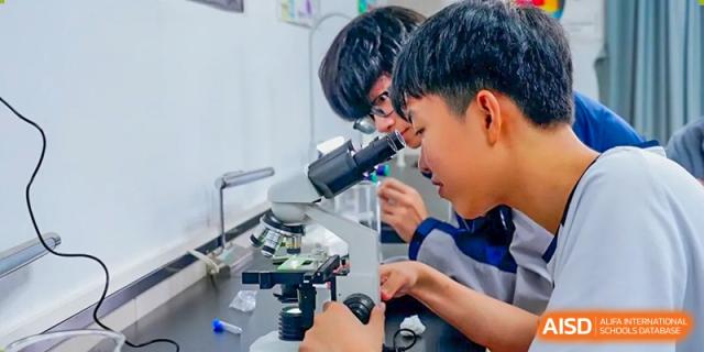 Students from The Affiliated School of JNU for Hong Kong & Macau Students (ASJ Dongguan) are using a microscope in a science lab.