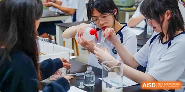 Students from The Affiliated School of JNU for Hong Kong & Macau Students (ASJ Dongguan) are conducting a science experiment with beakers and liquids.