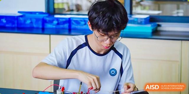 A student from The Affiliated School of JNU for Hong Kong & Macau Students (ASJ Dongguan) is focused on a detailed project or experiment.