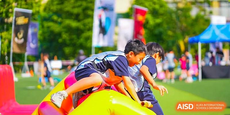 A student from The Affiliated School of JNU for Hong Kong & Macau Students (ASJ Dongguan) is participating in a sports event with a large yellow ball.