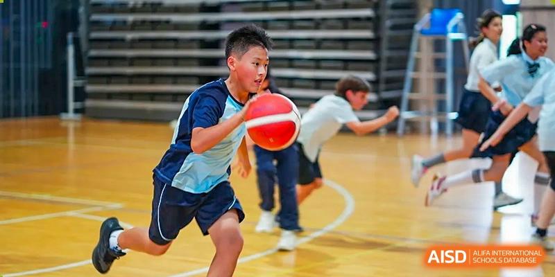 A student from The Affiliated School of JNU for Hong Kong & Macau Students (ASJ Dongguan) is dribbling a basketball during a game.