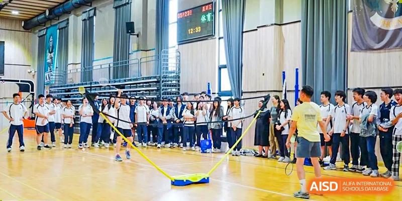 A group of students from The Affiliated School of JNU for Hong Kong & Macau Students (ASJ Dongguan) are playing a team game in a gymnasium.