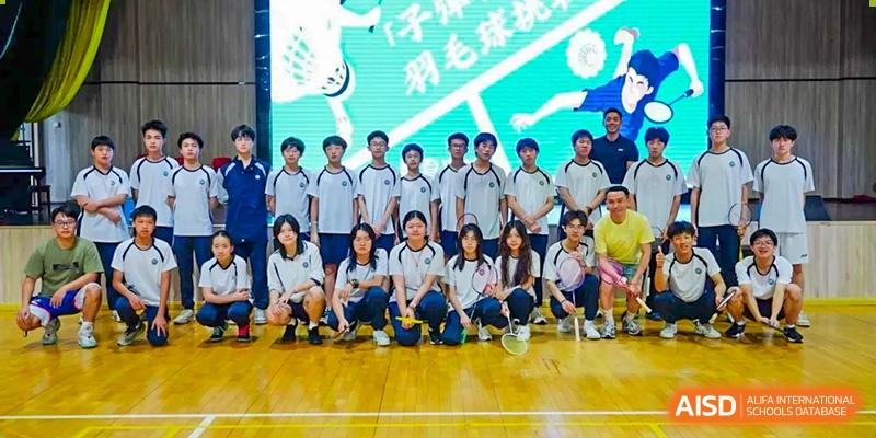 A group of students from The Affiliated School of JNU for Hong Kong & Macau Students (ASJ Dongguan) is posing for a photo under a banner.