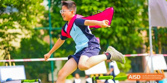 A student from The Affiliated School of JNU for Hong Kong & Macau Students (ASJ Dongguan) is running, with a red flag.