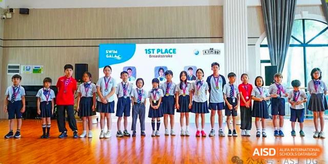 A group of students from The Affiliated School of JNU for Hong Kong & Macau Students (ASJ Dongguan) is posing for a photo with a trophy.