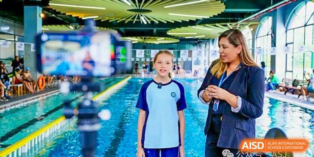 A female student from The Affiliated School of JNU for Hong Kong & Macau Students (ASJ Dongguan) is standing near a pool.