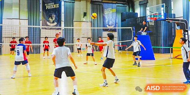 Students from The Affiliated School of JNU for Hong Kong & Macau Students (ASJ Dongguan) are playing badminton in a gymnasium.