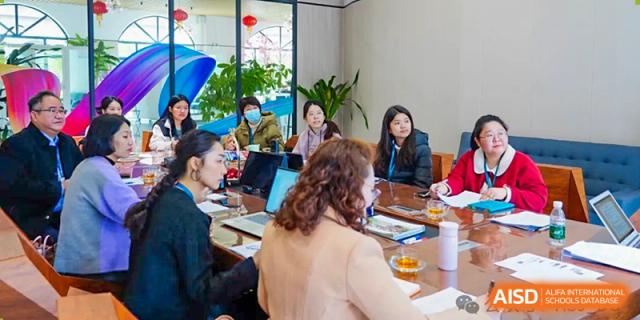 A group of adults, possibly teachers or parents, from The Affiliated School of JNU for Hong Kong & Macau Students (ASJ Dongguan) are sitting at a table.