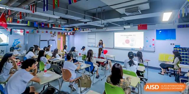 A teacher is standing at the front of a classroom, instructing students at Vanke Meisha Academy.