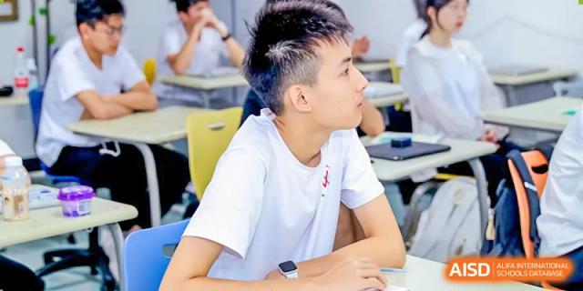 A male student is focused on a lesson while sitting at his desk in a classroom at Vanke Meisha Academy.