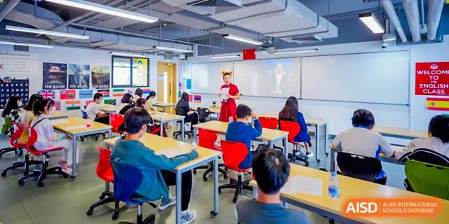 A teacher is standing at the front of a classroom, instructing students at Vanke Meisha Academy.