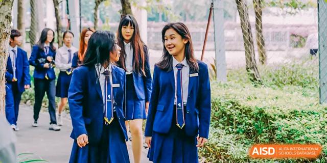 A group of students in blue school uniforms are walking outside and smiling at Vanke Meisha Academy.
