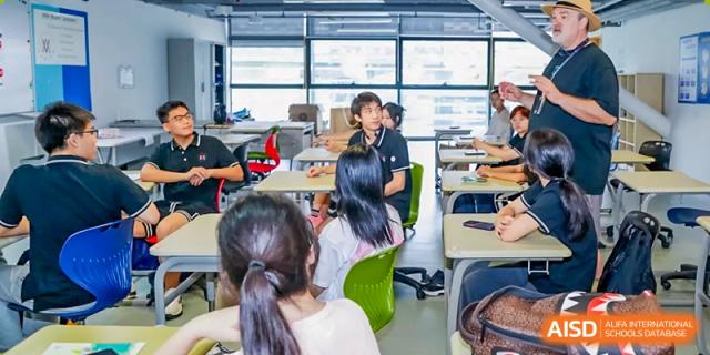 Students are listening to a teacher in a bright classroom at Vanke Meisha Academy.