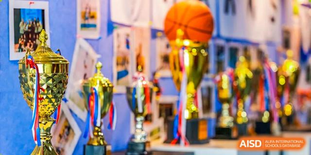 A close-up, blurred shot of a row of trophies, including a golden one with a basketball on top, at Vanke Meisha Academy.