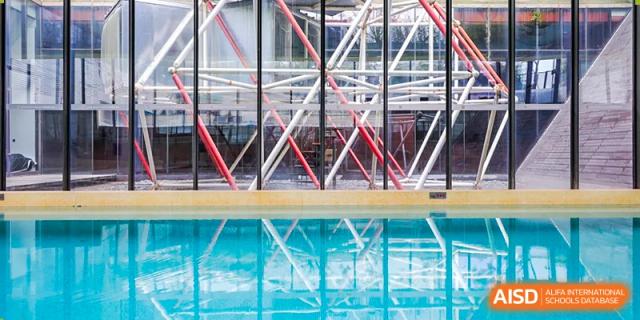 The unique, modern architecture of a building is reflected in a nearby body of water at Vanke Meisha Academy.