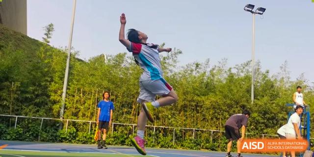 A male student is captured mid-air while playing a game of badminton at Vanke Meisha Academy.