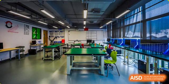 An empty indoor room with a green ping pong table in the center at Vanke Meisha Academy.