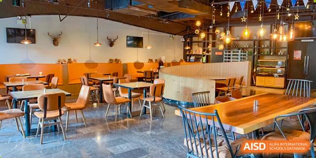 A bright and modern cafe with wooden tables and chairs at Vanke Meisha Academy.
