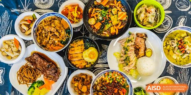 A variety of delicious and healthy-looking meals are arranged on a patterned tablecloth at Vanke Meisha Academy.