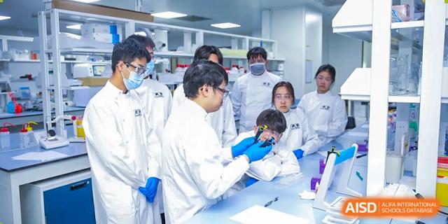 Students in lab coats and gloves conducting a science experiment at Yew Chung International School of Chongqing