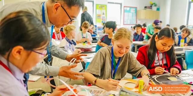 A teacher smiling and interacting with students in a classroom at Yew Chung International School of Chongqing