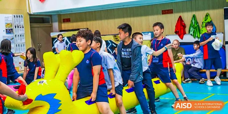 A group of students playing with a large yellow inflatable at Yew Chung International School of Chongqing