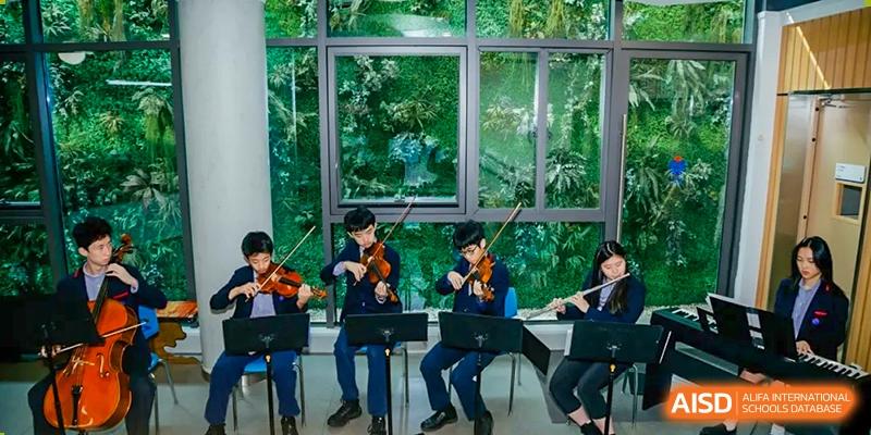 Students playing violins and other string instruments during a performance at Yew Chung International School of Chongqing