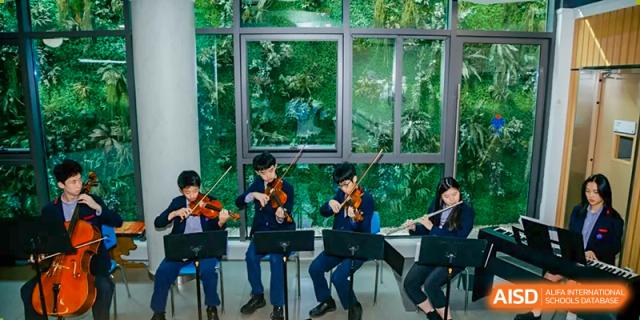 Students playing violins and other string instruments during a performance at Yew Chung International School of Chongqing