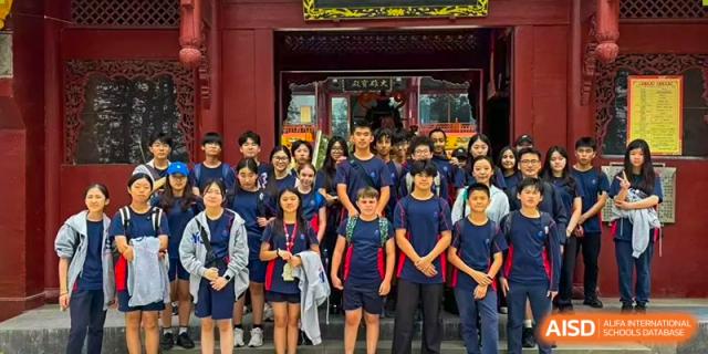 A large group of students posing in front of a traditional Chinese building at Yew Chung International School of Chongqing