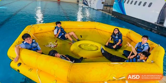 A student playing with a large yellow inflatable in a swimming pool at Yew Chung International School of Chongqing