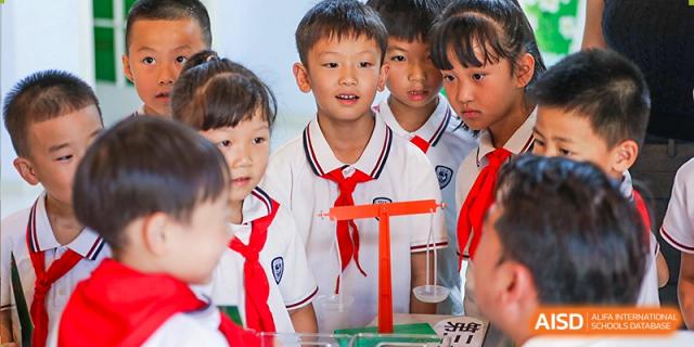 Young students from Yiwu International Academy working with a balance scale in a science or math activity.