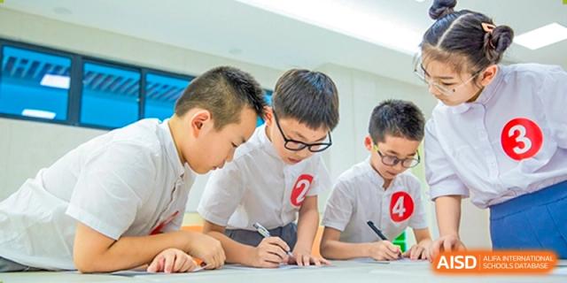 Two male students from Yiwu International Academy collaborating and writing during a classroom activity.