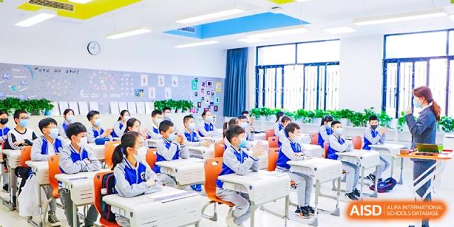 Young students from Yiwu International Academy seated at desks in a bright, modern classroom.