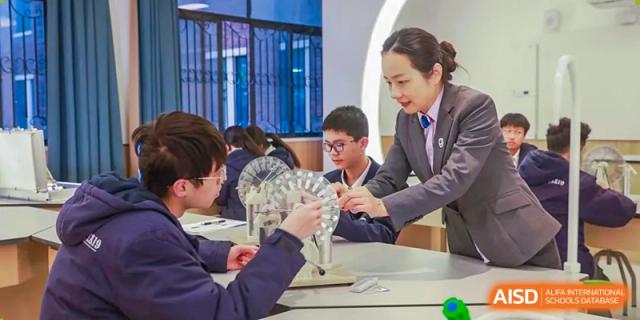 A teacher assisting students with a hands-on modeling project or demonstration at Yiwu International Academy.