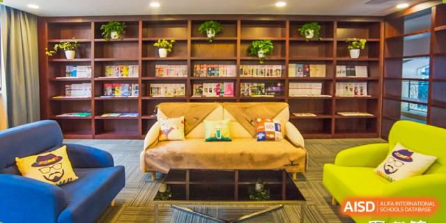 A cozy, well-stocked reading nook or lounge with a brown couch and bookshelf, a student area at Yiwu International Academy.