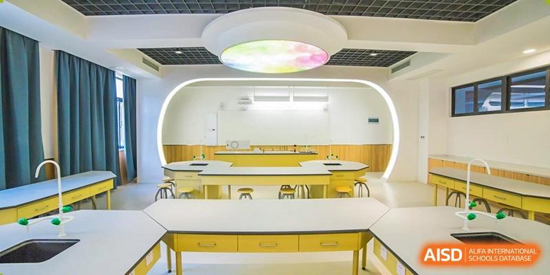 A bright, modern science laboratory or classroom with yellow desks and a unique light fixture at Yiwu International Academy.