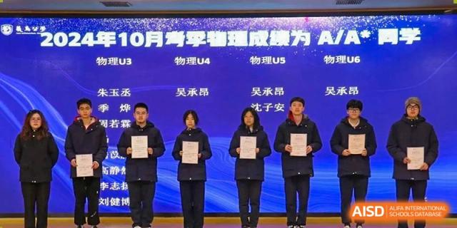 Students from Yiwu International Academy holding certificates and posing on a stage during an awards ceremony.