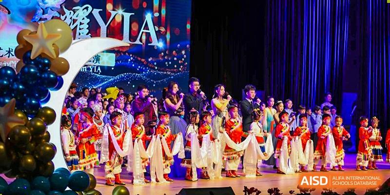 A group of young students from Yiwu International Academy performing a traditional or cultural dance on a large stage.