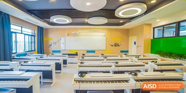 An empty classroom with rows of desks and keyboards for a music or IT class at Yiwu International Academy.