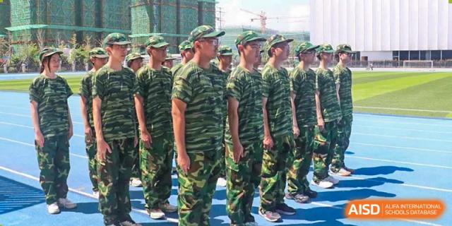 A line of students in camouflage military-style uniforms during a training or outdoor activity at Yiwu International Academy.