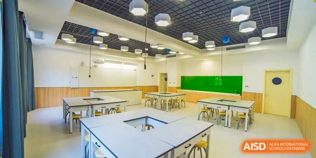 A bright, clean classroom or seminar room with light wooden tables and chairs at Yiwu International Academy.