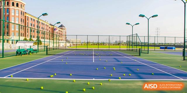 An outdoor tennis court scattered with many tennis balls, a sports facility at Yiwu International Academy.