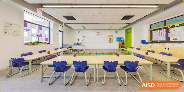 A modern, bright classroom or learning space with small tables and blue chairs at BASIS International School Hangzhou (BIHZ).
