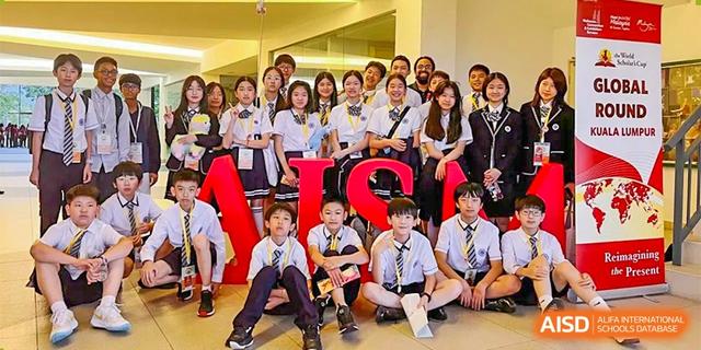 A large group of smiling students and teachers posing together for a group photo indoors at BASIS International School Hangzhou (BIHZ).